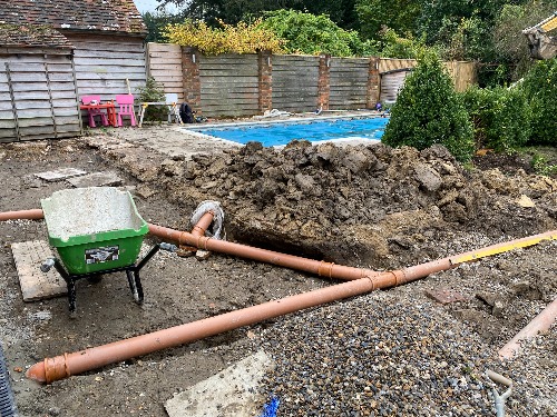 Perforated land drainage pipe installed in clean gravel channel with geotextile wrap