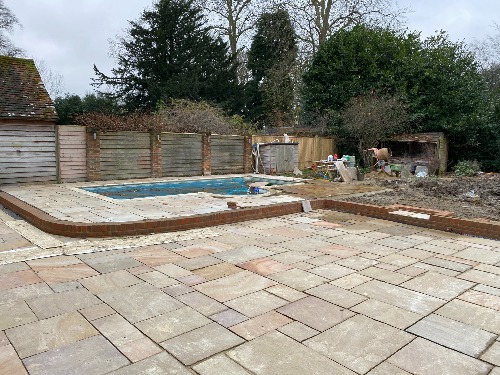 Indian sandstone paving being laid around an existing pool in Cobham