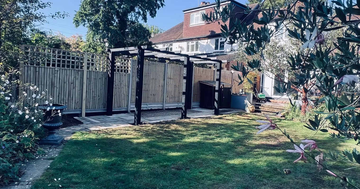 Bespoke black wooden pergola in tidy garden, making space for activities