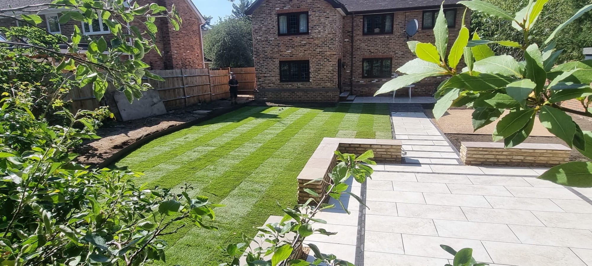 Landscaped garden with lawn and sandstone paving, Surrey, by Flourish Landscaping