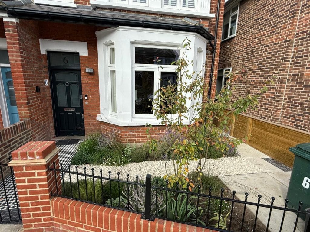 Period front garden in Kingston with cast-iron railings and a paved path to a bay-fronted house, by Flourish Landscaping
