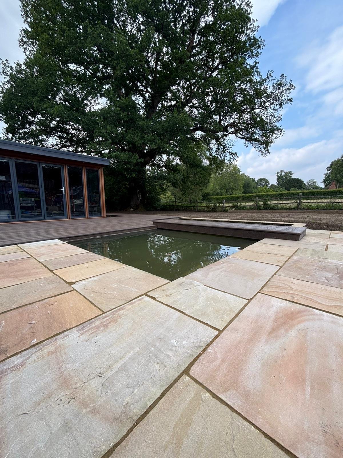 Natural pond with sandstone paving and marginal planting by Flourish Landscaping