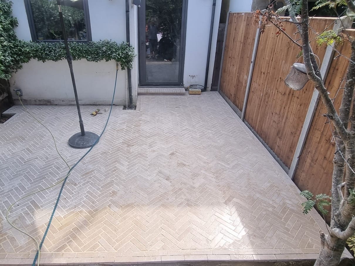 Freshly laid herringbone limestone patio outside the garden doors of a New Malden home