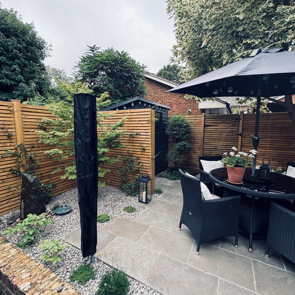 Small courtyard garden in Surbiton with a limestone terrace running into gravel, slatted timber screens and an ornamental Acer, by Flourish Landscaping