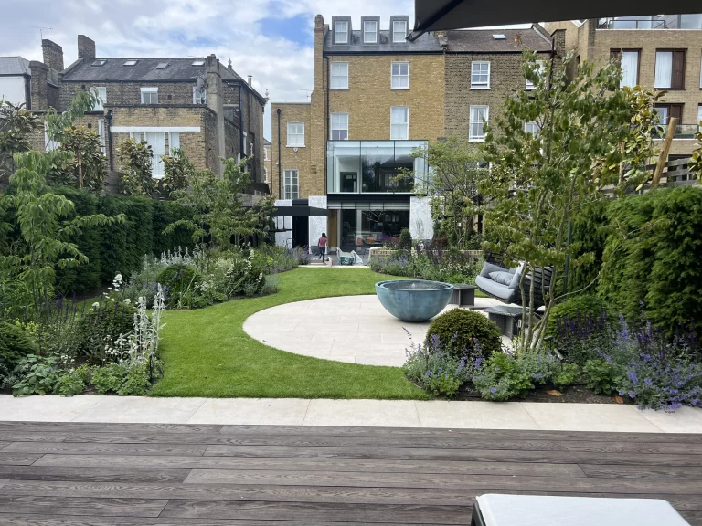 Completed town garden with curved lawn, circular terrace, bowl water feature and lush planting, Wandsworth