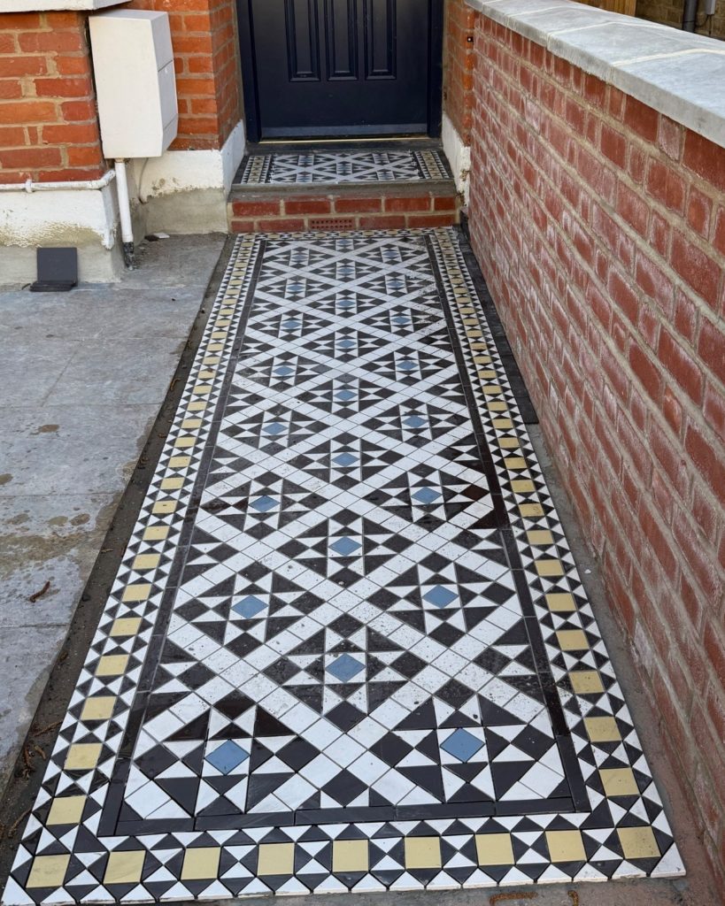New Victorian-style geometric tiled front path in black and white stars with blue centres and a buff and black border, with a matching tiled step, by Flourish Landscaping in Kingston